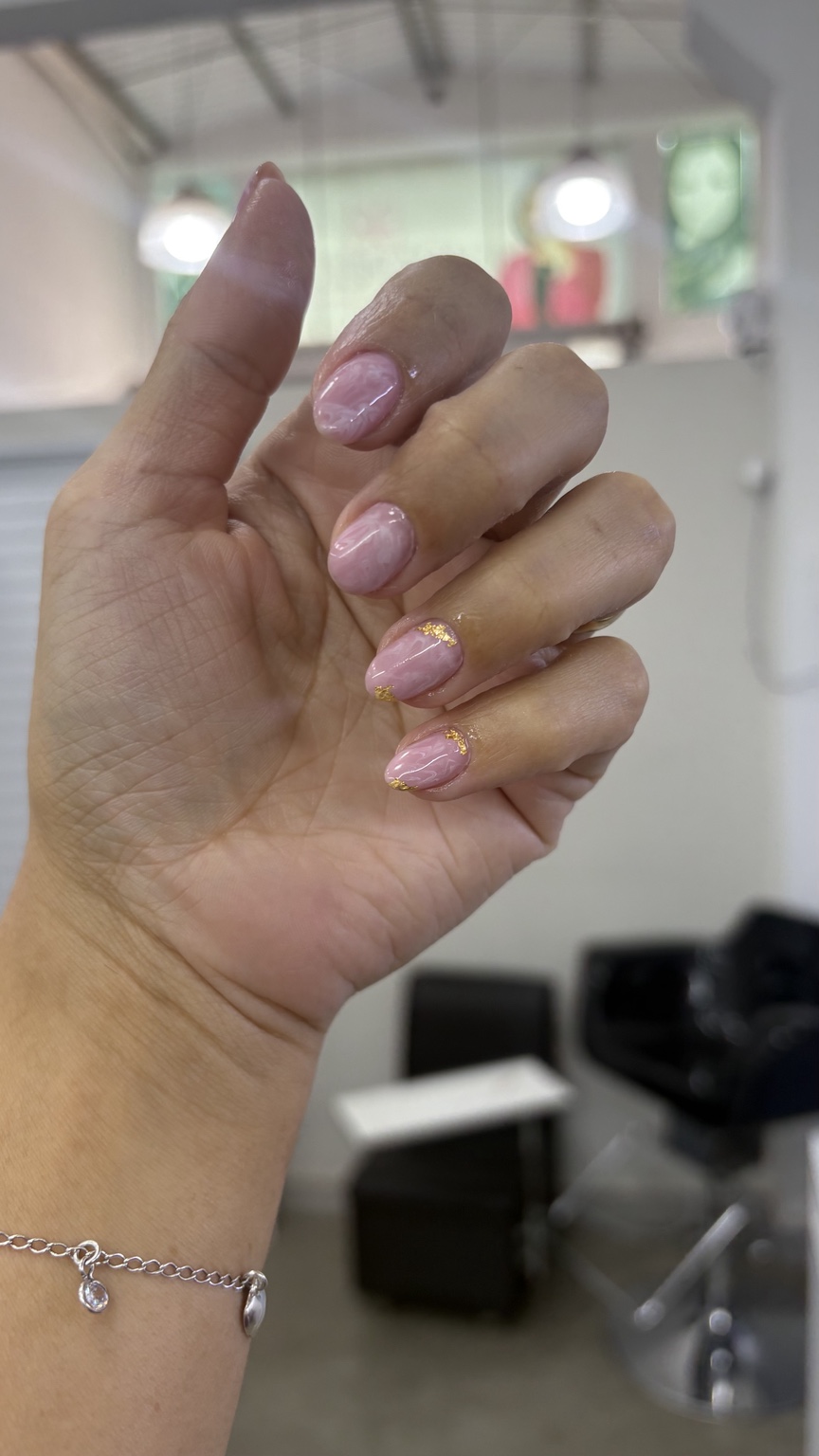 Unhas com esmaltação rosada e detalhes dourados